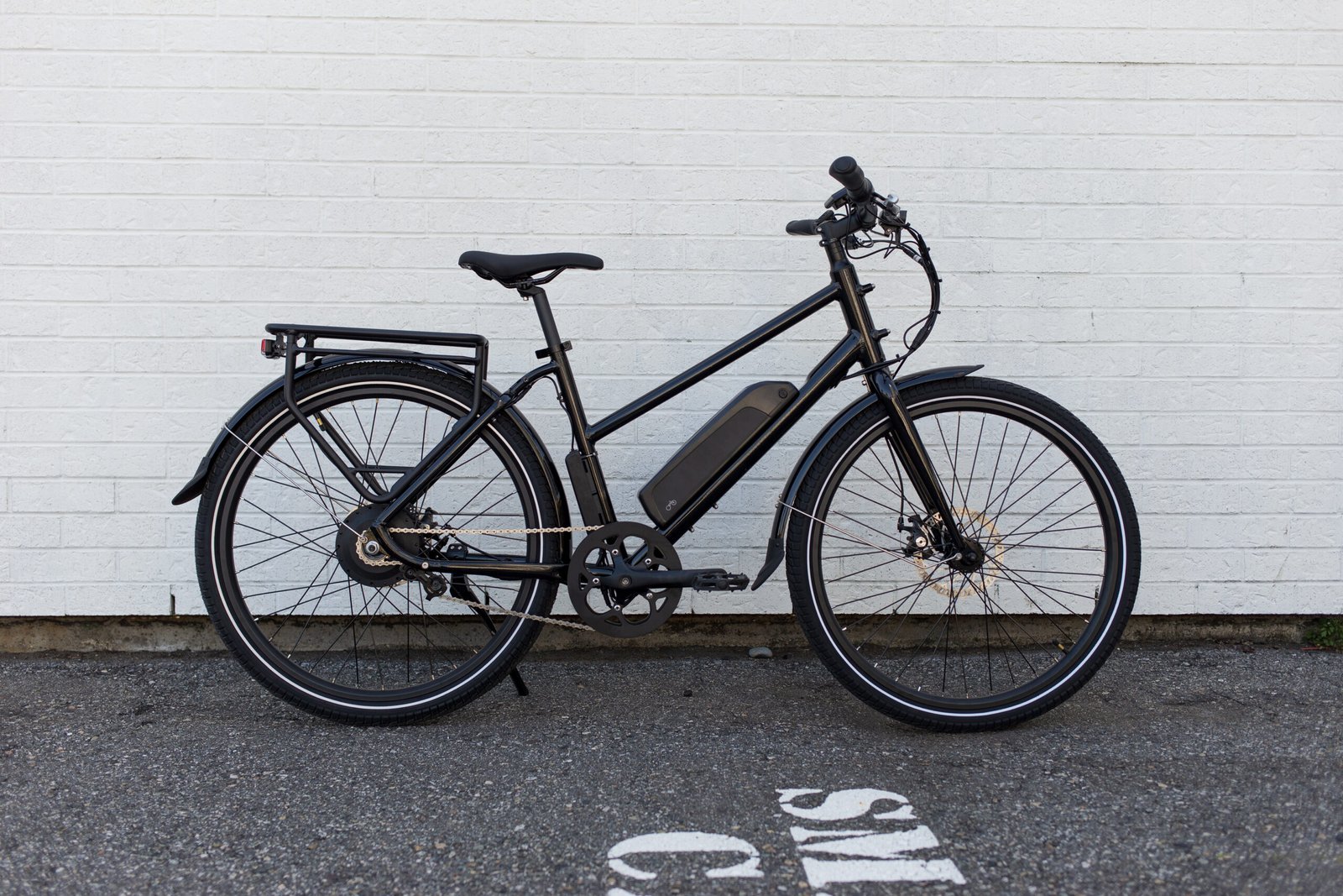Modern black electric bicycle against white brick wall